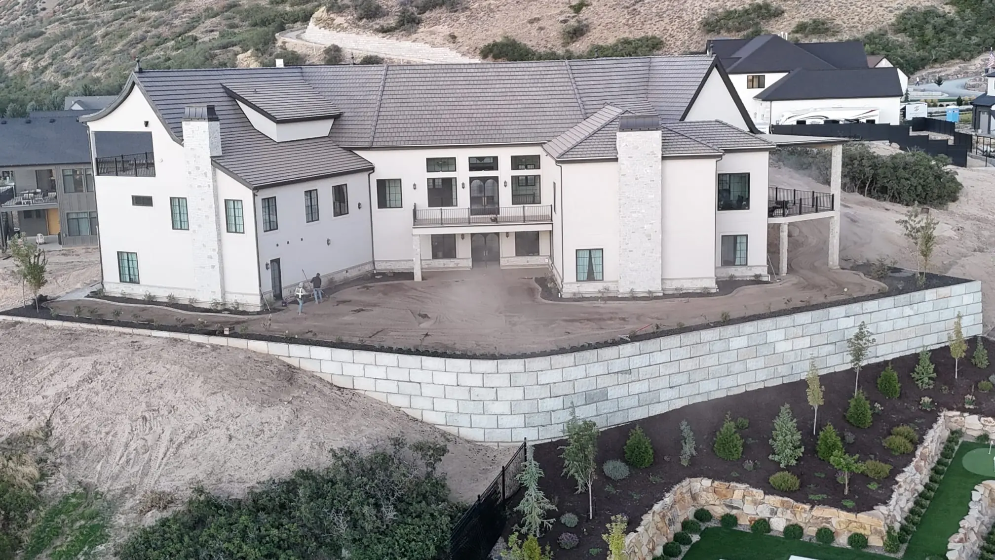 Aerial view of a curved block retaining wall supporting a hillside home's backyard