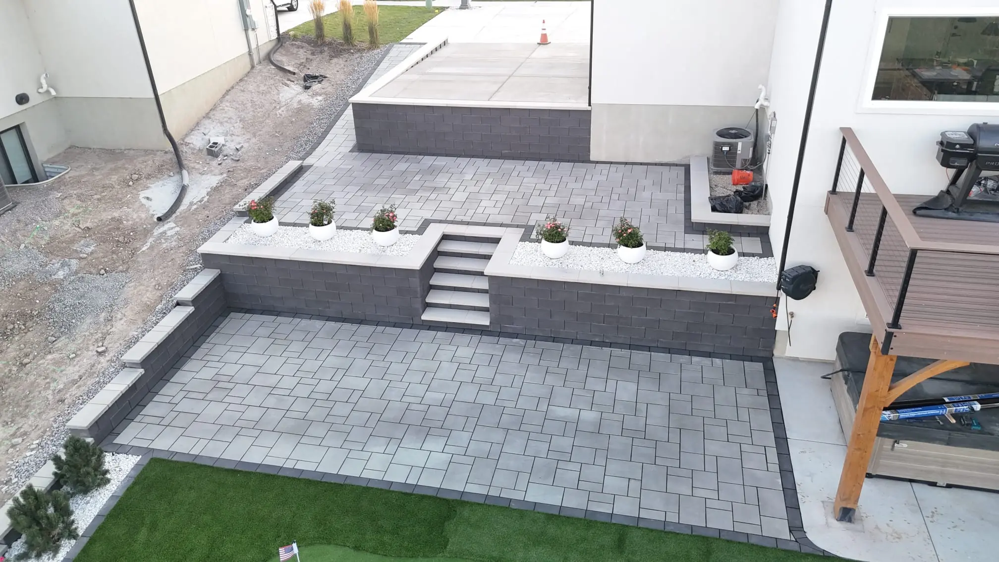 Two-level paver patio connected by steps between block walls with planters