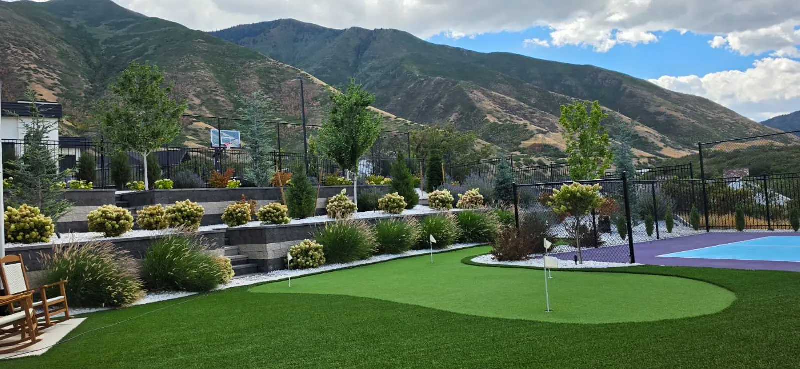 Custom backyard putting green beside a sports court with mountain views