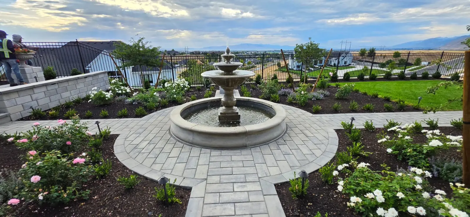 Tiered garden fountain centered in a circular paver walkway with mountain views